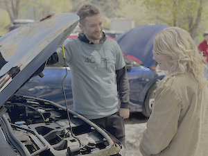 Chris showing someone under the hood of an electric car.